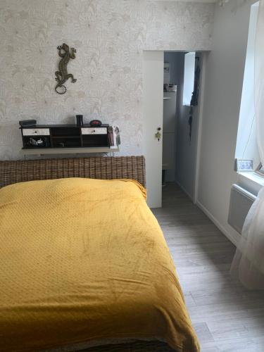 une chambre avec un lit avec une couverture jaune dans l'établissement JOUANNEAU, au Mans