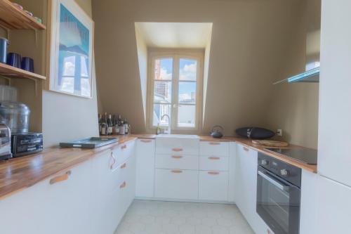 une cuisine avec des armoires blanches et une fenêtre dans l'établissement Loft Saint-Germain des près Vavin, à Paris