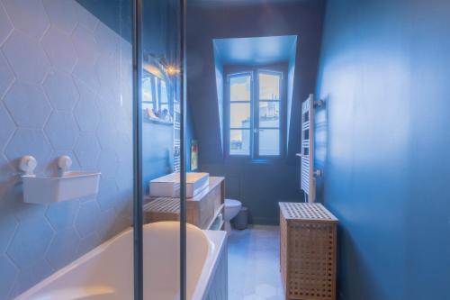 La salle de bains bleue est pourvue d'une baignoire et d'un lavabo. dans l'établissement Loft Saint-Germain des près Vavin, à Paris