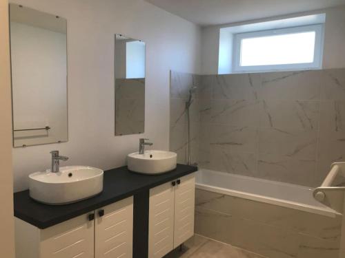 ein Badezimmer mit zwei Waschbecken, einem Spiegel und einer Badewanne in der Unterkunft Maison familiale au cœur du Lot in Lanzac