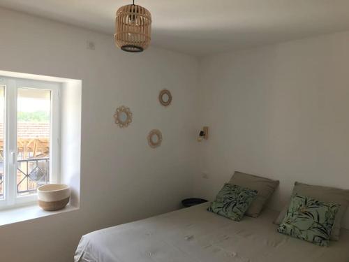 ein weißes Schlafzimmer mit einem Bett und einem Fenster in der Unterkunft Maison familiale au cœur du Lot in Lanzac