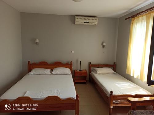 um quarto com 2 camas e uma janela em Ραπτη Θεοδωρα em Paralia Vrachou