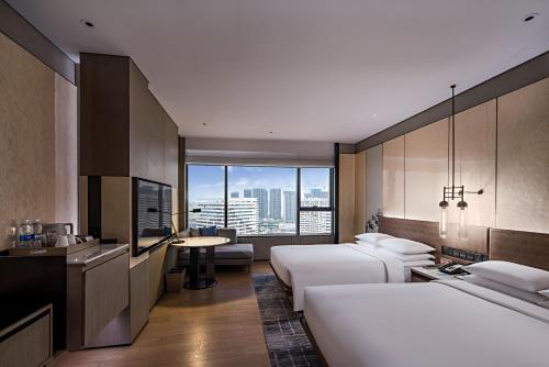 a hotel room with two beds and a view of a city at Wuhan Marriott Hotel Hankou in Wuhan