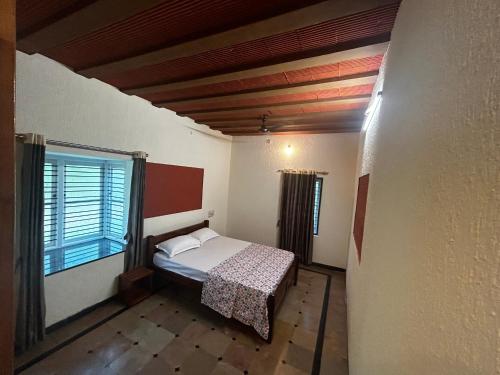 um pequeno quarto com uma cama e uma janela em The Coco Ranch em Chāmundi