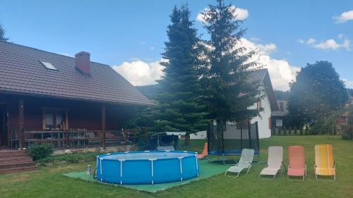 a group of chairs and a pool in a yard at Pokoje Gościnne u Huberta in Soblówka