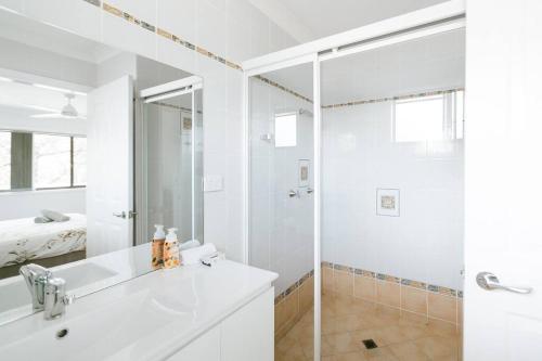 a white bathroom with a shower and a sink at Wanda House - Close to beach Linen Pets in Salamander Bay