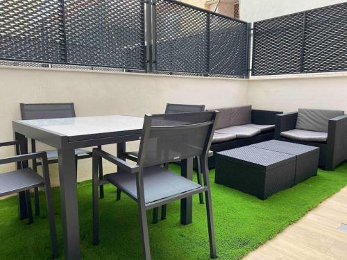 einen Tisch und Stühle sowie eine Bank mit grünem Gras in der Unterkunft Moderno loft en Barajas in Madrid