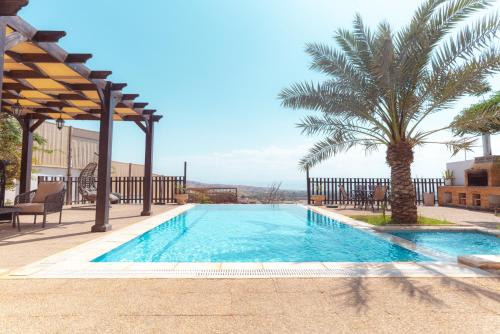 a swimming pool with a palm tree in the background at Little Venice Chalet- Private Villa- Dead Sea Jordan in Sowayma