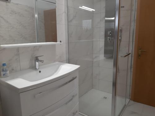 a white bathroom with a sink and a shower at Madunić in Podstrana