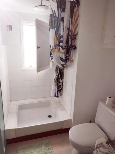 uma casa de banho branca com uma banheira e um WC em Appartement à 50 m de la plage em Audierne