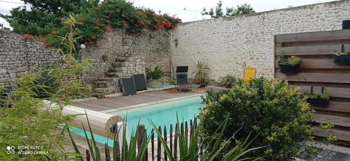 un patio trasero con piscina y pared de ladrillo en la Belle Endormie, en Saint-Just