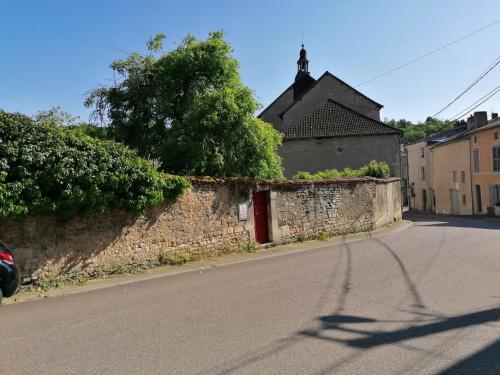 a street with a stone wall and a red door at Le gite de la Licorne in Saint-Mihiel