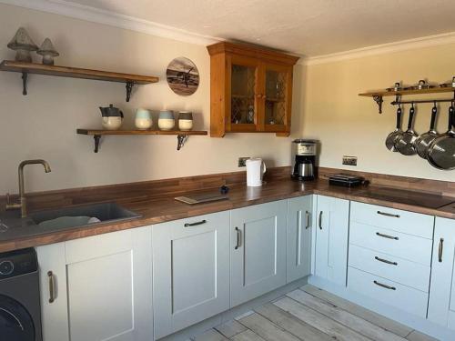 a kitchen with white cabinets and a wooden counter top at Southend, Mull of Kintyre, Campbeltown in Campbeltown