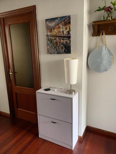 een lamp op een wit dressoir naast een deur bij Habitación privada para 2 personas a 10 min de la playa in Santander