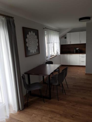 a dining room with a table and chairs and a kitchen at Agroturystyka Koronkowe Zacisze in Koniaków