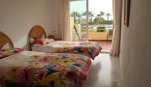 two beds in a room with a view of a balcony at 2 bedroom apartment overlooking Mediterranean, 2 outdoor pools in Mijas Costa
