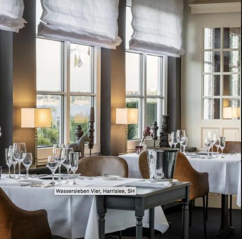 a dining room with white tables and chairs and windows at NEU! ERSTBEZUG! Vollsanierte Fewo mit Blick auf die Flensburger Förde in Harrislee