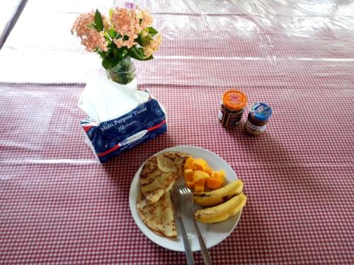 um prato de alimentos com bananas e frutas sobre uma mesa em Lorenso Cottage em Manado