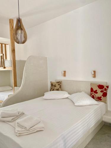 Bett mit weißer Bettwäsche und Kissen in einem Zimmer in der Unterkunft Fikas Hotel in Naxos Chora