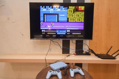 a computer monitor on a table with two video game controllers at Twin Tower Residence by Nest Home【5 mins walk to CIQ】 in Johor Bahru