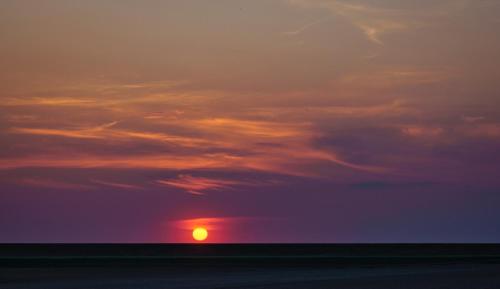 a sunset with the sun in the sky at De Berin in Westhoek