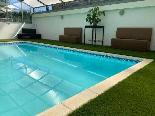 - une piscine d'eau bleue et 2 chaises dans l'établissement Maison des 4 Vallées, à La Barthe-de-Neste