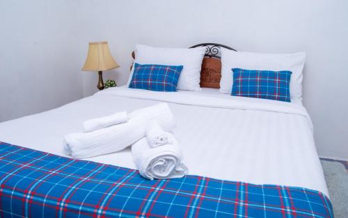 a white bed with blue pillows and towels on it at Elegant Touch Home - 2 Bedroom House in Karen in Nairobi