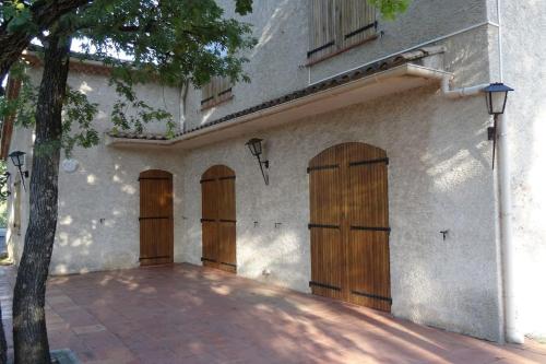 un edificio con cuatro puertas de madera. en Villa avec piscine, Jacuzzi 10/12 personnes, en Cuers