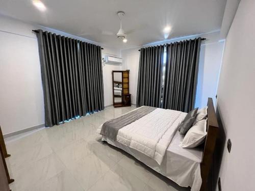 a bedroom with a bed and two large windows at Luxury 2BR Apartment in Ratmalana in Ratmalana South