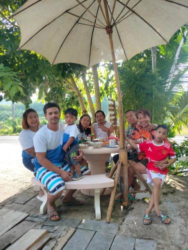 a group of people sitting at a table under an umbrella at Baan Namthip Homestay Trang บ้านน้าทิพย์ โฮมสเตย์ตรัง in Ban Huai To (1)