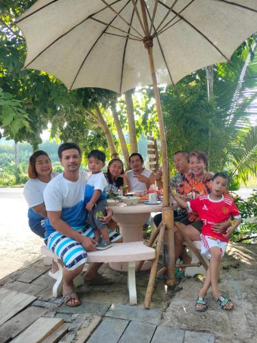 a group of people sitting at a table under an umbrella at Baan Namthip Homestay Trang บ้านน้าทิพย์ โฮมสเตย์ตรัง in Ban Huai To (1)