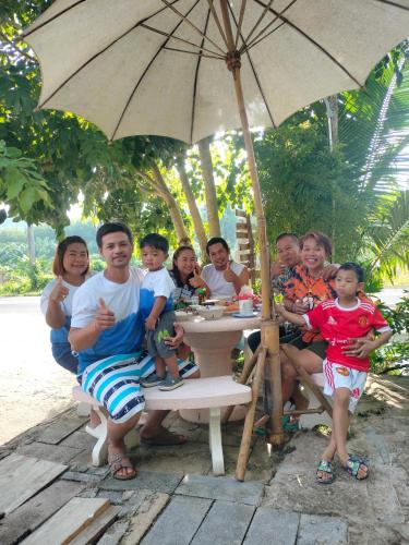 a group of people sitting at a table under an umbrella at Baan Namthip Homestay Trang บ้านน้าทิพย์ โฮมสเตย์ตรัง in Ban Huai To (1)