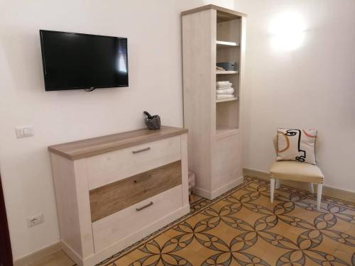 ein Wohnzimmer mit einem TV und einem Stuhl in der Unterkunft CASA VERDINA, nel cuore di Alghero in Alghero