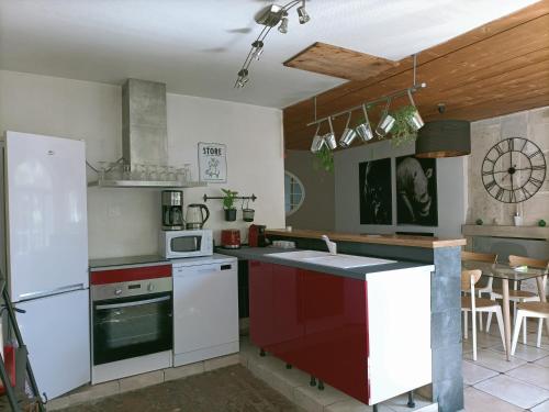 une cuisine avec des appareils électroménagers blancs et des armoires rouges dans l'établissement Le relais des Colombes, à Creully
