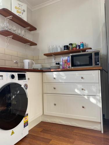 a kitchen with a washing machine and a microwave at Stylish Lake Albert Cottage, Wagga Wagga in Wagga Wagga