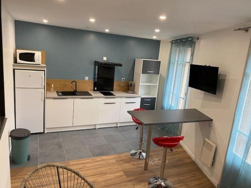 een keuken met witte kasten en een tafel en stoelen bij Appartement refait à neuf in Argelès-sur-Mer