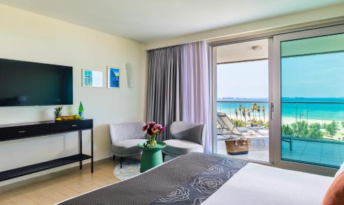 a hotel room with a bedroom with a view of the ocean at West All Suites Hotel Ashdod in Ashdod