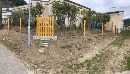 a playground with a yellow gate in the dirt at Petite maison VILLEFORT in Villefort