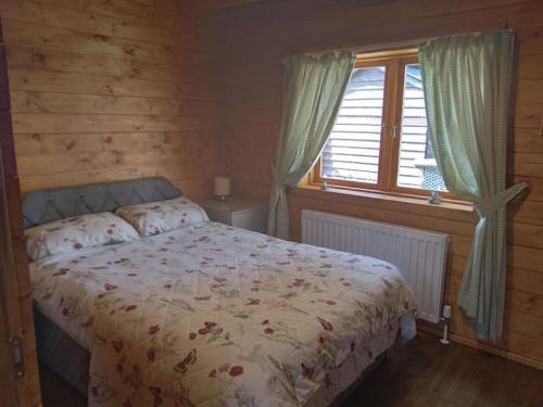 a bedroom with a bed and a window at Bishy Barnabees country lodge with hot tub in Swaffham