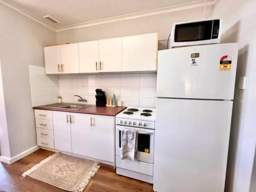una cucina con armadietti bianchi e frigorifero bianco di Stylish Apartment by the sea a Port Hedland