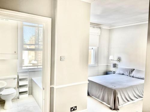 um quarto branco com uma cama e um WC em Lovely 2-beds flat in the heart of Knightsbridge em Londres
