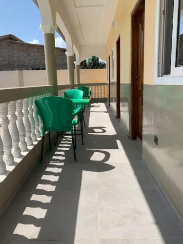 a row of green tables and chairs on a porch at pavillon « lilas » à dagué-togo in Dagé