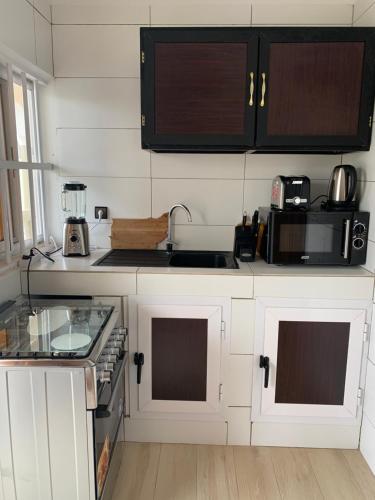 uma cozinha com armários brancos e um forno com placa de fogão em pavillon « lilas » à dagué-togo em Dagé