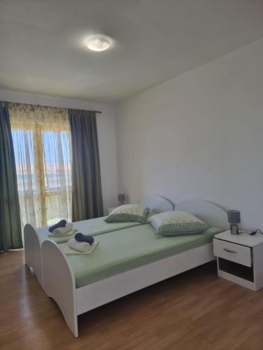 a bedroom with a large bed with green sheets and a window at APARTMANI ALEN in Dinjiška