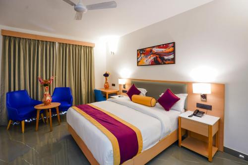 a hotel room with a large bed and blue chairs at Hotel Meraden Opus , Anjuna Beach Goa in Anjuna