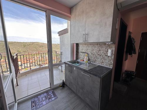 a kitchen with a sink and a balcony at Sea Sky View Apartments in Balchik