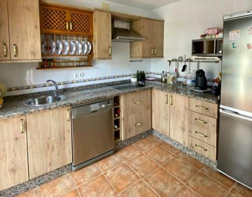 uma cozinha com armários de madeira e electrodomésticos de aço inoxidável em CASA RURAL EN URB LAs TRUCHAS-EL BOSQUE em El Bosque