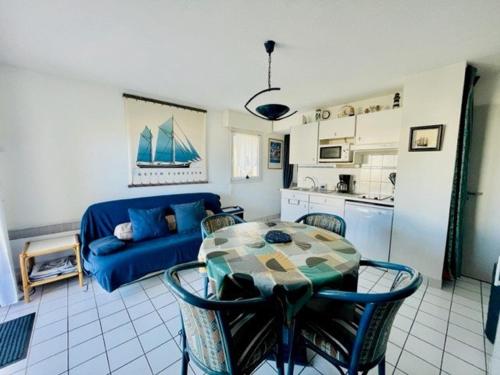 un salon avec une table et un canapé bleu dans l'établissement Quiberon - Appartement 3 pièces, 41m², 2 chambres, terrasse, parking, animaux admis - FR-1-478-95, à Quiberon
