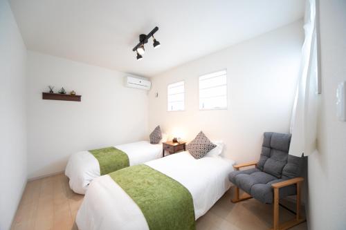 2 camas y una silla en una habitación en Nagashima Riverside Condominium, en Hakuro