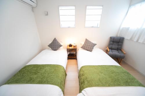 two twin beds in a small room with a chair at Nagashima Riverside Resort 2 in Hakuro